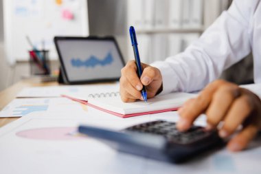 Finansal gelir ve karı kontrol etmek için hesap makinesine basan iş adamının elini kapat