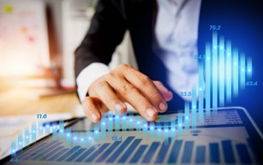 İşadamı dizüstü bilgisayarda grafiğe bakıyor ve işaret ediyor.