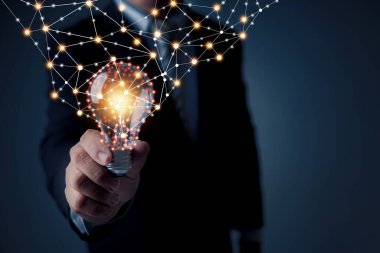 Fikir ve teknoloji yenilik konsepti, iş adamı elinde elektrik hattı ile parlayan ampul tutuyor