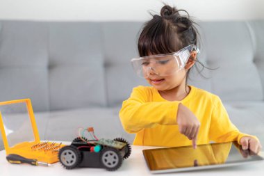 Küçük kızlar atölyede robot araba kodlarken eğleniyorlar.