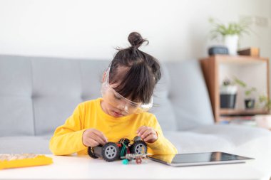 Küçük kızlar atölyede robot araba kodlarken eğleniyorlar.