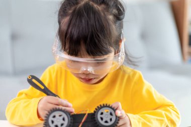 Küçük kızlar atölyede robot araba kodlarken eğleniyorlar.