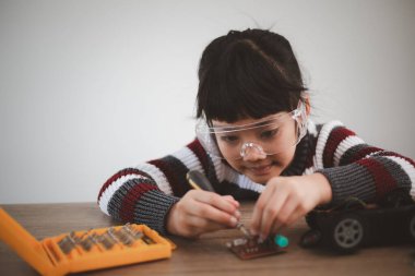 Küçük kızlar atölyede robot araba kodlarken eğleniyorlar.