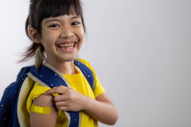  Aşılandıktan ya da aşılandıktan sonra kolunu sarı bandajla gösteren Asyalı genç kız, çocuk aşısı, covid delta aşısı konsepti.