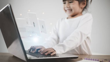 Bilgisayarı online yayın için kullanan Asyalı bir kız, internetten video izliyor, canlı eğitim, özel ders, çevrimiçi öğrenim, eğitim, evde eğitim. Covid-19 salgını sırasında....