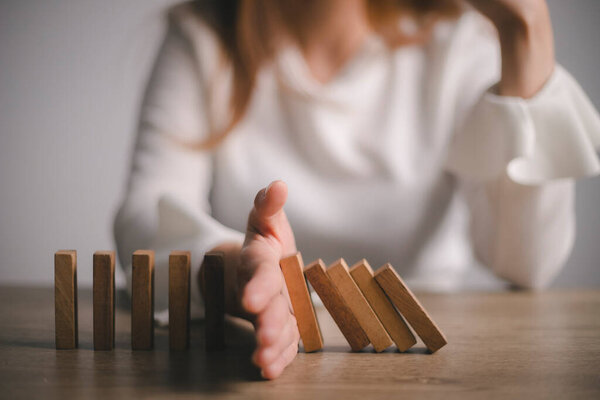 Risk and Strategy in Business, Hand stopping wooden block domino business crisis effect or risk protection concept, prevention and development to stability