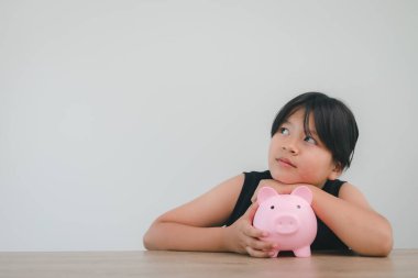 Tatlı Asyalı kız gelecek için para biriktirmek adına kumbaraya para koyuyor.