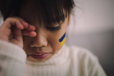 Ukrayna bayrağı taşıyan bir çocuk ağlıyor. Üzüntü, umut özlemi. Savaştan kalan çocukların gözyaşları. Sivillerin tahliyesi. Ukrayna 'ya Özgürlük