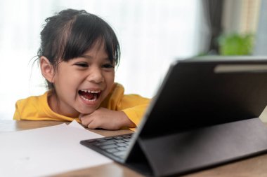 Asyalı küçük kız internetten ders alıyor ve evde karantina koranavirüs salgını konsepti için mutlu.