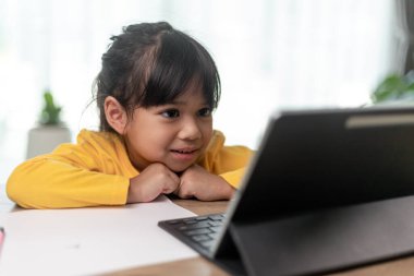 Asyalı küçük kız internetten ders alıyor ve evde karantina koranavirüs salgını konsepti için mutlu.
