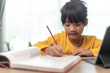 Elinde kağıt kalem tutan çocuk, internette dijital tablet kullanarak ev ödevi için bilgi arayan çocuk, evde eğitim, e-öğrenim online eğitim
