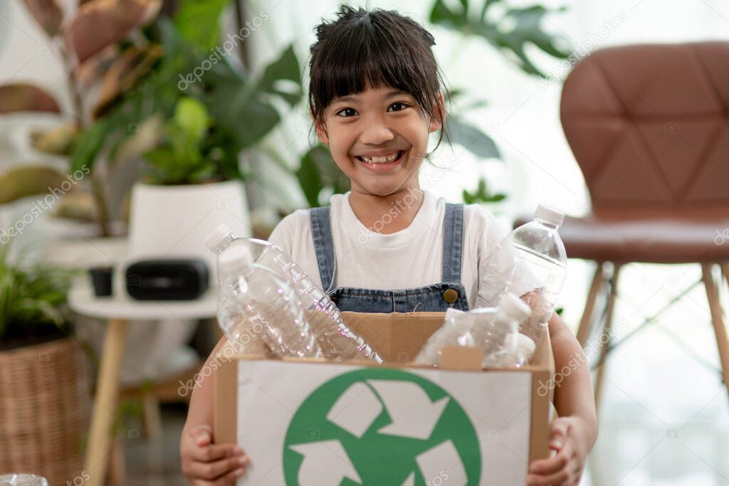 Girl looking at camera and holding plastic bottles for recycling