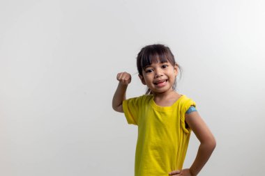 COVID 19 Çocuk Aşısı konsepti. Stüdyo, ilk aşısını aldıktan sonra Asyalı güzel bir kızın portresi. Bağışıklık, Güvenli, Uygun, Okula Dönüş.