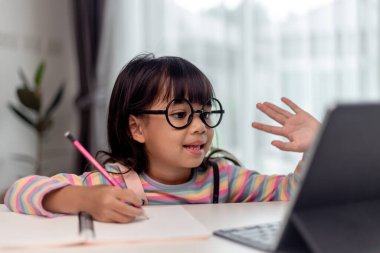 Asyalı küçük kız internetten ders alıyor ve evde karantina koranavirüs salgını konsepti için mutlu.