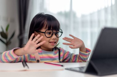 Asyalı küçük kız internetten ders alıyor ve evde karantina koranavirüs salgını konsepti için mutlu.