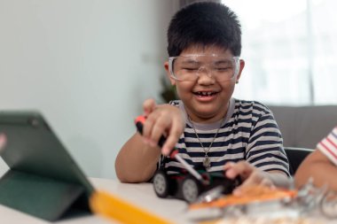 Genç Asyalı öğrenci evde uzaktan öğreniyor robot araba kodlaması ve elektronik kablo ile STEM, STEAM, matematik mühendisi çocuklar için robotik bilim teknolojisi bilgisayar kodu..