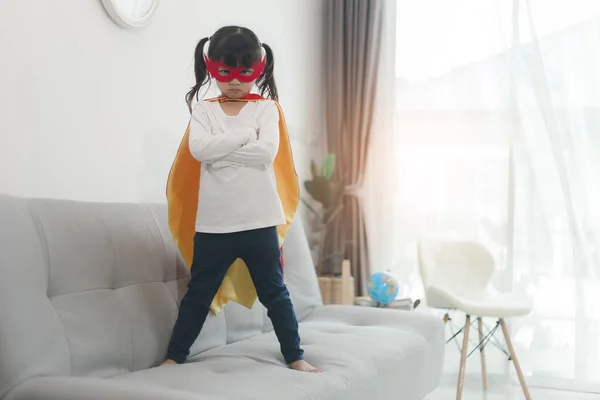 儿童女孩在一个超级英雄服装与面具和红色斗篷在家中 — 图库照片
