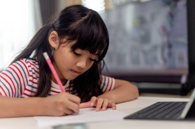 Sevimli Asyalı çocuk öğrenme sınıfı çalışması evde tabletten video çağrısı ile çevrimiçi. Sosyal uzaklık kavramı