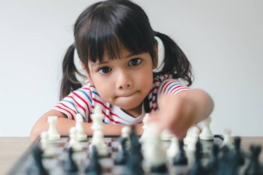 Evde satranç oynayan Asyalı küçük kız. Bir satranç oyunu.