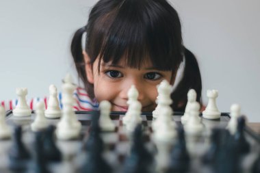 Evde satranç oynayan Asyalı küçük kız. Bir satranç oyunu.