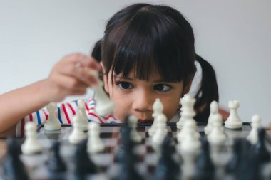 Evde satranç oynayan Asyalı küçük kız. Bir satranç oyunu.