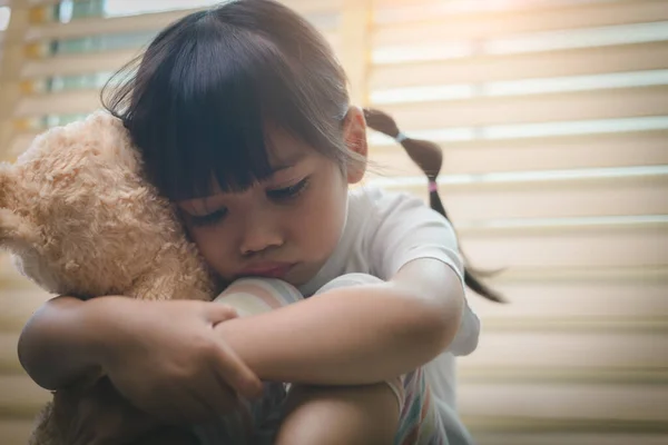 把寂寞的小女孩抱在怀里 一个人坐在家里 让不快乐的孩子等着父母 想问题 想家庭关系不好 想心理创伤 — 图库照片