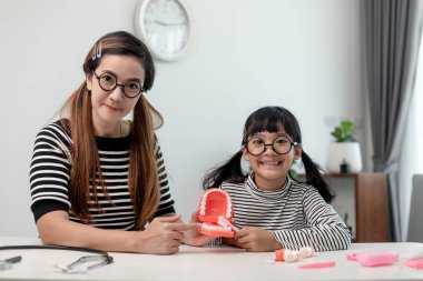 Anne, kızına dişlerini doğru fırçalamayı öğretiyor.