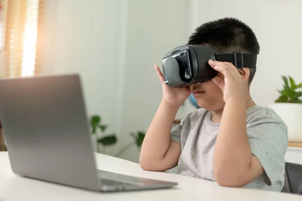 schoolboy wearing vr glasses in classroom. unaltered, education, virtual reality simulator, technology and school concept.