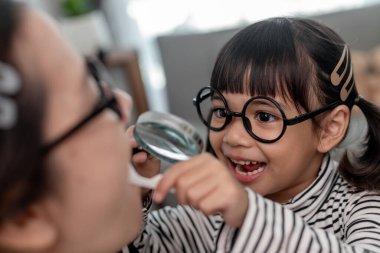 Geleceğin doktoru evde annesinin takma dişlerini kontrol ediyor..