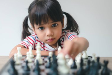 Evde satranç oynayan Asyalı küçük kız. Bir satranç oyunu.
