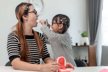 Geleceğin doktoru evde annesinin takma dişlerini kontrol ediyor..