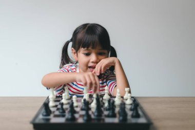 Evde satranç oynayan Asyalı küçük kız. Bir satranç oyunu.