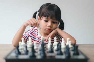 Evde satranç oynayan Asyalı küçük kız. Bir satranç oyunu.