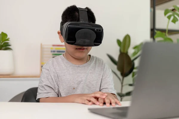 Asian Little boy with VR glasses studying sciences at home,curious student wears a virtual reality headset to study science home online study futuristic lifestyle learning