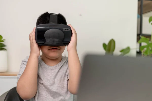 Asian Little boy with VR glasses studying sciences at home,curious student wears a virtual reality headset to study science home online study futuristic lifestyle learning