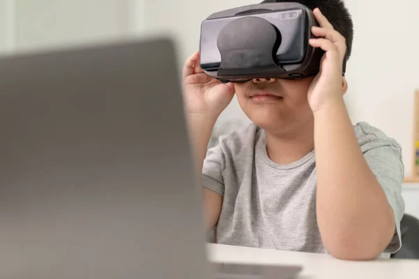 Asian Little boy with VR glasses studying sciences at home,curious student wears a virtual reality headset to study science home online study futuristic lifestyle learning