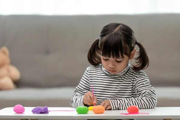 Asian kids play with clay molding shapes, learning through play