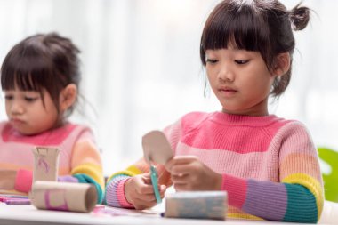 Küçük Asyalı bir kızın portresi, okuldaki DIY dersinde kağıt kesme aktiviteleriyle ilgili. Makas kesme kağıdı..