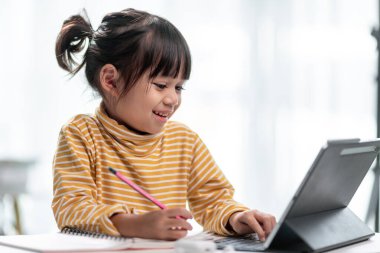 Online öğrenim sınıfındaki Asyalı kız öğrenciler evde Tablet ile çevrimiçi öğrenim görüyorlar.