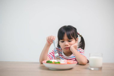 Nutrition & healthy eating habits for kids concept. Children do not like to eat vegetables. Little cute girl refuses to eat healthy vegetables.