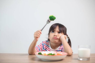 Nutrition & healthy eating habits for kids concept. Children do not like to eat vegetables. Little cute girl refuses to eat healthy vegetables.