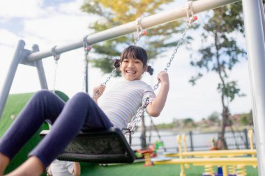 A little girl is having fun riding a swing.