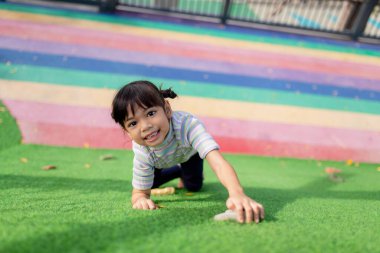 Cute Asian girl having fun trying to climb on artificial boulders at schoolyard playground, Little girl climbing up the rock wall, Hand Eye Coordination, Skills development