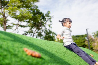 Cute Asian girl having fun trying to climb on artificial boulders at schoolyard playground, Little girl climbing up the rock wall, Hand Eye Coordination, Skills development