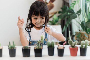 Kid gently touches the new stem of the cactus he grows with care nature education, Montessori, and observation skills concepts.