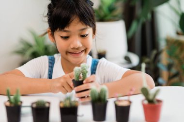 Kid gently touches the new stem of the cactus he grows with care nature education, Montessori, and observation skills concepts.