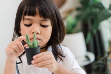 Kid gently touches the new stem of the cactus he grows with care nature education, Montessori, and observation skills concepts.