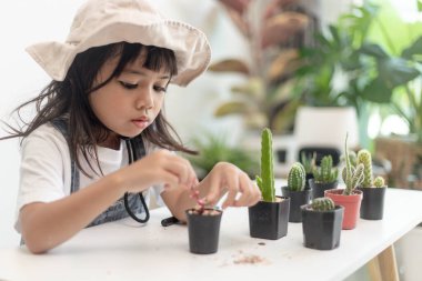 Kid gently touches the new stem of the cactus he grows with care nature education, Montessori, and observation skills concepts.