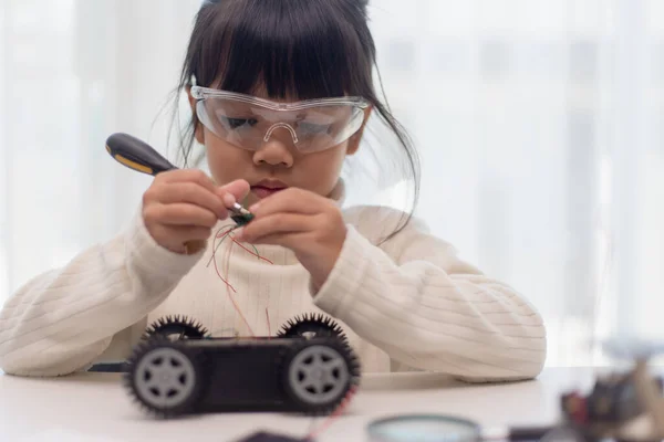 Asian students learn at home in coding robot cars and electronic board cables in STEM, STEAM, mathematics engineering science technology computer code in robotics for kids concept.