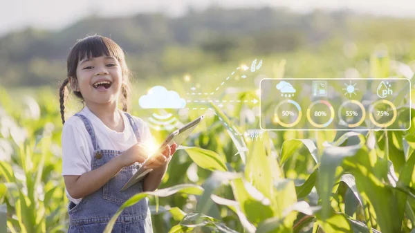 The little girl uses a tablet to analyze the growth of plants in the agricultural plot and visual icon., the agricultural technology concept. smart farming learning Concept